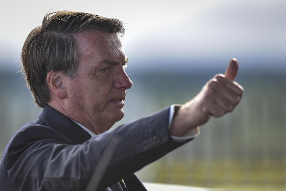 Brazil's President Jair Bolsonaro greets supporters and journalists as he arrives to give a news conference on the new coronavirus at Planalto presidential palace in Brasilia, Brazil, Friday, March 27, 2020. Even as coronavirus cases mount in Latin America’s largest nation, Bolsonaro is calling the pandemic a momentary, minor problem and saying strong measures to contain it are unnecessary. (AP Photo/Andre Borges)