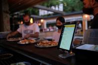 Employees pick up the pizzas near an IPad with the "Funky Pay" app, at Funky Pizza restaurant, where the app replaces waiters, in Palafrugell