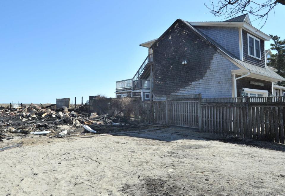 Rubble from homes destroyed by a fire sits next to a house scorched by intense flames on Glades Road in Scituate on Friday night.