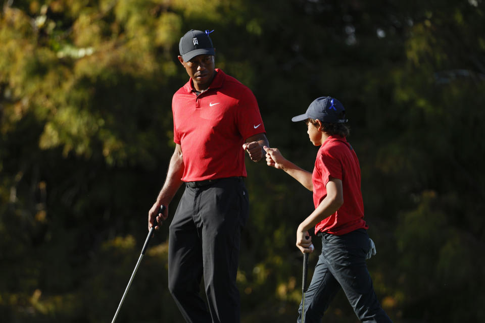 FILE -Tiger Woods fist bumps his son Charlie Woods on the 16th green during the second round of the PNC Championship golf tournament, Sunday, Dec. 19, 2021, in Orlando, Fla. Speculation for 2022 starts with where Woods will show up next on the PGA Tour. (AP Photo/Scott Audette, File)