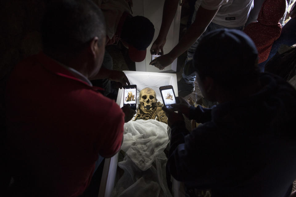 Telatives take cell phone pictures of the remains of Fortunate Ventura Huamacusi, a man who was killed by the Peruvian army in 1983, before placing the coffin in its niche at the Rosaspata cemetery in Peru's Ayacucho province on Aug. 14, 2018. Thousands of Peruvian families who have spent decades wondering about loved ones who disappeared during years of bloody conflict between the state and Maoist guerrillas have new hopes for getting the closure they have been searching for. (AP Photo/Rodrigo Abd)