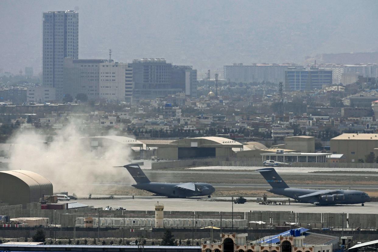 US soldiers stand on the tarmac as an US Air Force aircraft prepares for take off from the airport in Kabul on Monday  (AFP via Getty Images)