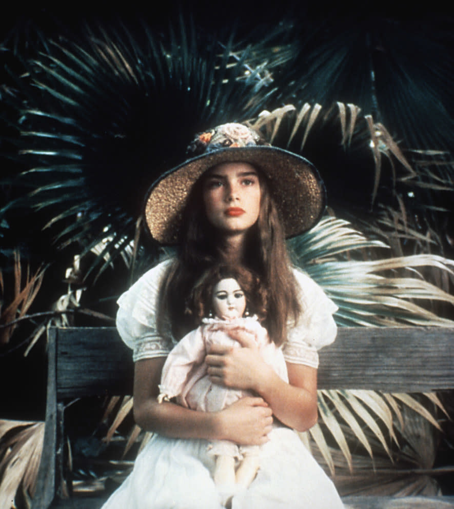 Brooke Shields in a scene from "Pretty Baby," holding a doll, wearing a straw hat