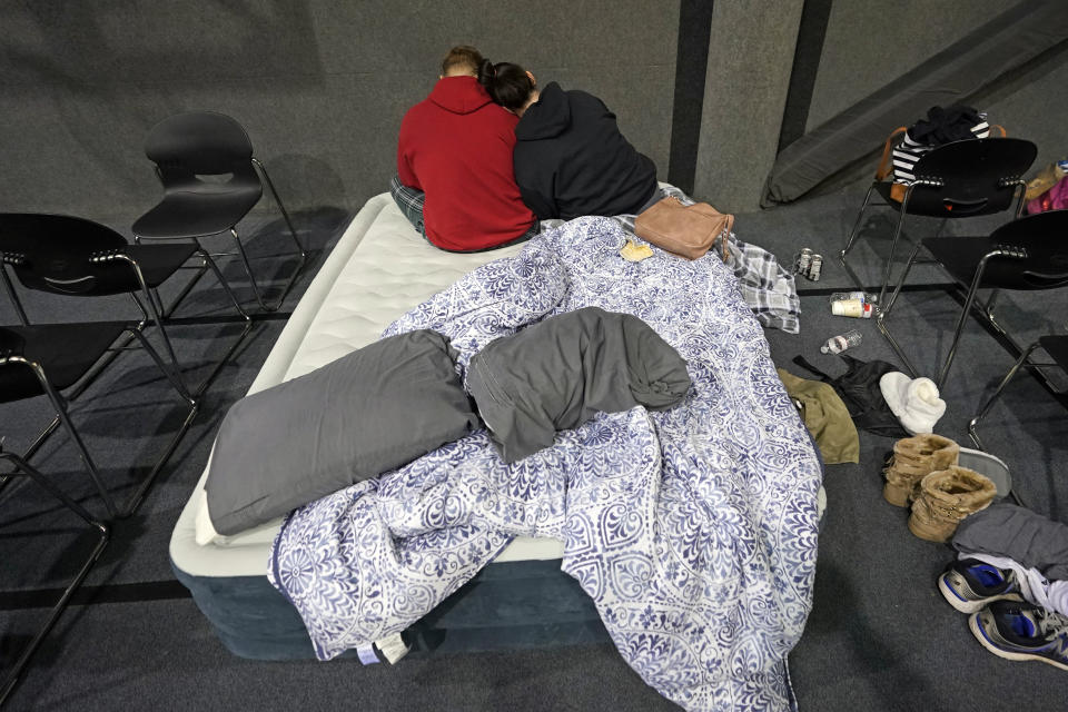 Bethany Fischer, right, rests her head on the shoulder of her husband Nic, while staying at a church warming center Tuesday, Feb. 16, 2021, in Houston. The couple, who lost power at their home on Monday, are part of the more than 4 million people in Texas who still had no power a full day after historic snowfall and single-digit temperatures created a surge of demand for electricity to warm up homes unaccustomed to such extreme lows, buckling the state's power grid and causing widespread blackouts. (AP Photo/David J. Phillip)