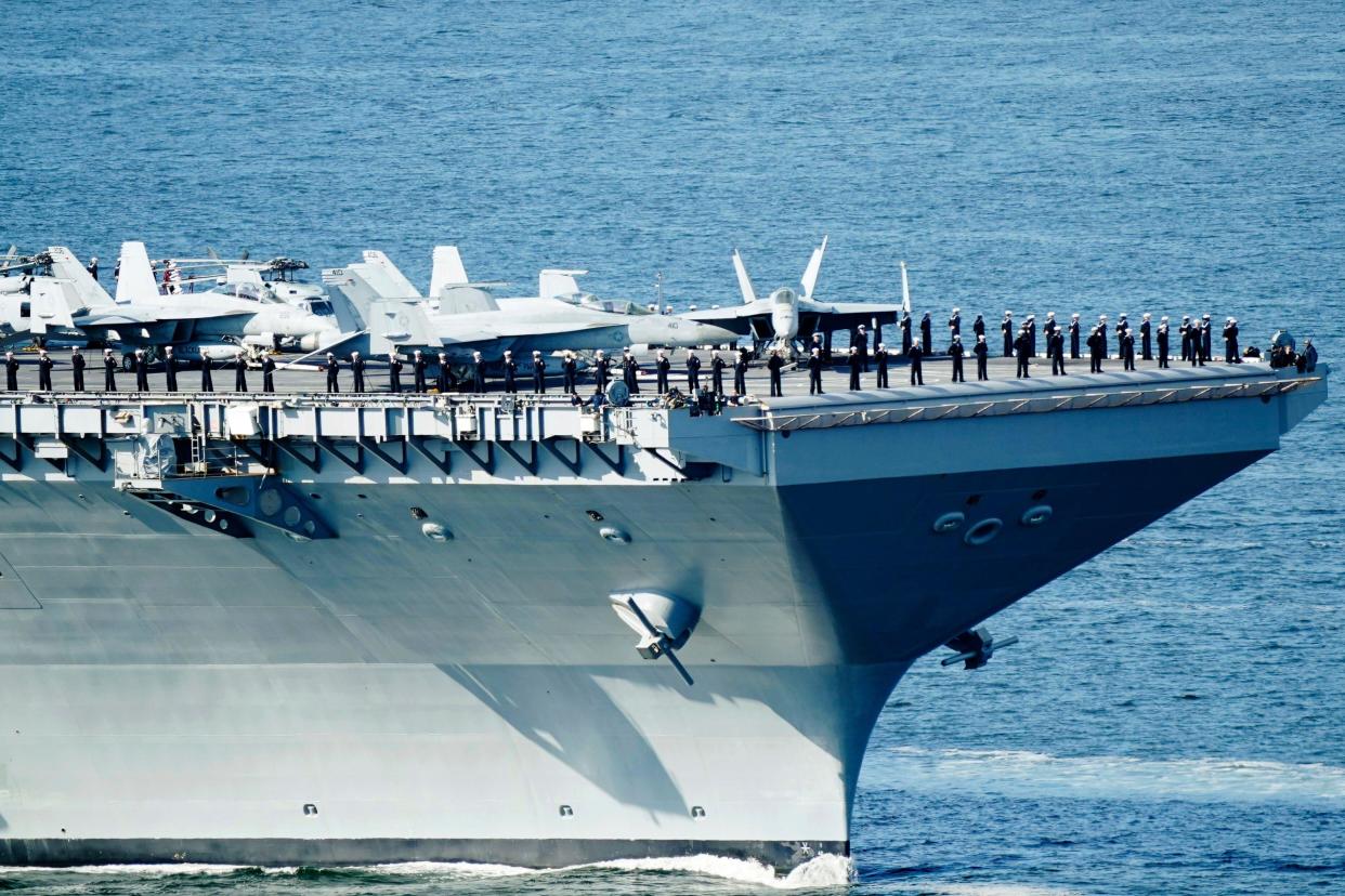 The crew of the aircraft carrier USS Gerald R. Ford stands on the flight deck as the carrier passes on its way into the Oslo Fjord, at Drobak, Norway, Wednesday, May 24, 2023. The ship is the world's largest warship and will be in port of Oslo for four days. (Terje Pedersen/NTB Scanpix via AP)