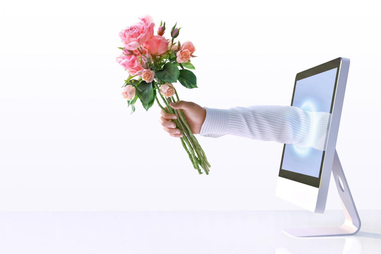 Would flattery from an AI set your heart aflutter? <a href="https://www.gettyimages.com/detail/photo/male-hand-reaching-out-from-computer-screen-holding-royalty-free-image/1682239343" rel="nofollow noopener" target="_blank" data-ylk="slk:quantic69/iStock via Getty Images;elm:context_link;itc:0;sec:content-canvas" class="link ">quantic69/iStock via Getty Images</a>