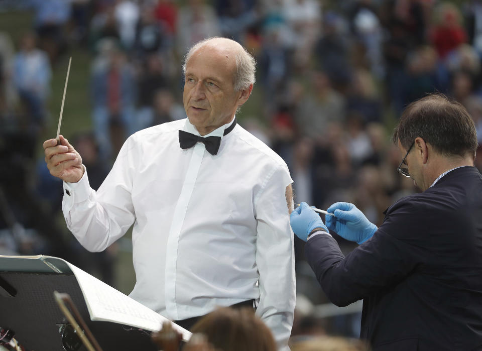 Ivan Fischer, founder of the Budapest's Festival Orchestra, receives his third dose of the COVID-19 vaccine as he conducts the orchestra, during their free concert in Budapest, Hungary, Wednesday August 25, 2021. The Budapest Festival Orchestra promoted the need for booster shots and encouraged Hungarians to stay alert since the risk of becoming infected is still high as the delta variant spreads. AP Photo/Laszlo Balogh