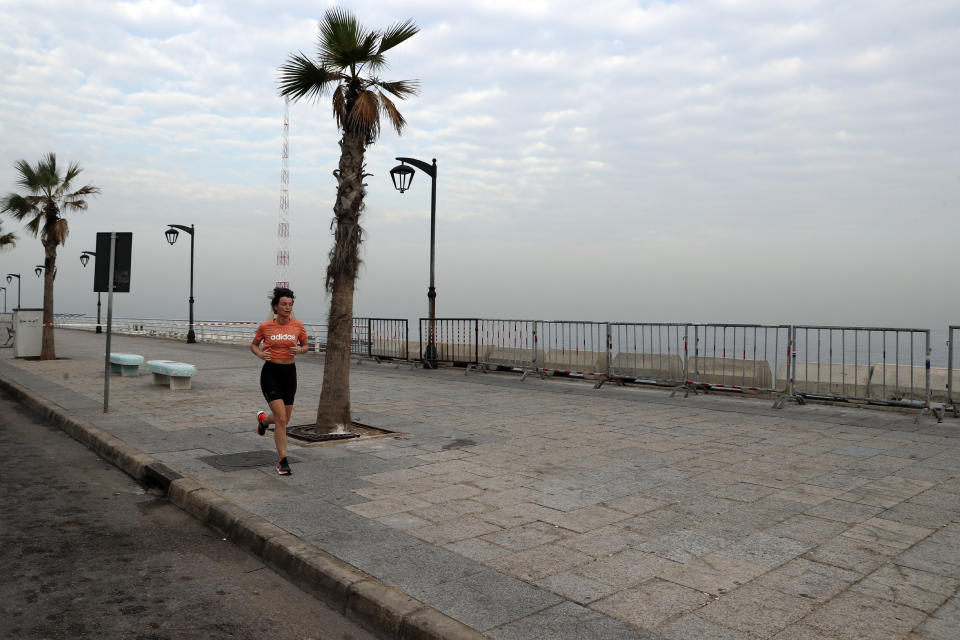 A woman runs on the empty waterfront promenade as the country begins a three-week lockdown to limit the spread of coronavirus amid a post-holiday surge in the past 10 days in Beirut, Lebanon, Thursday, Jan. 7, 2021. (AP Photo/Bilal Hussein)