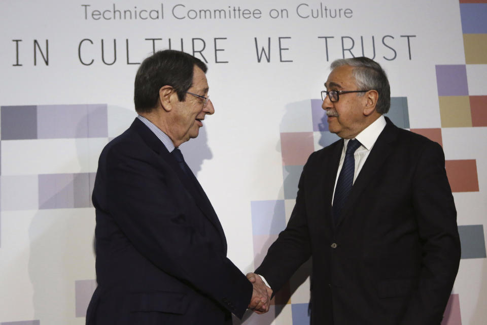 Cyprus' President Nicos Anastasiades, left, and Mustafa Akinci, the leader of the ethnically divided island's breakaway Turkish Cypriots, shake hands during a culturally significant paintings and audio visual recordings that were recently exchanged as part of an effort to boost confidence between the ethnically divided island nation's two communities, at the Ledra Palace Hotel inside the UN controlled buffer zone in divided capital Nicosia, Cyprus, Monday, Feb. 3, 2020. (AP Photo/Petros Karadjias)