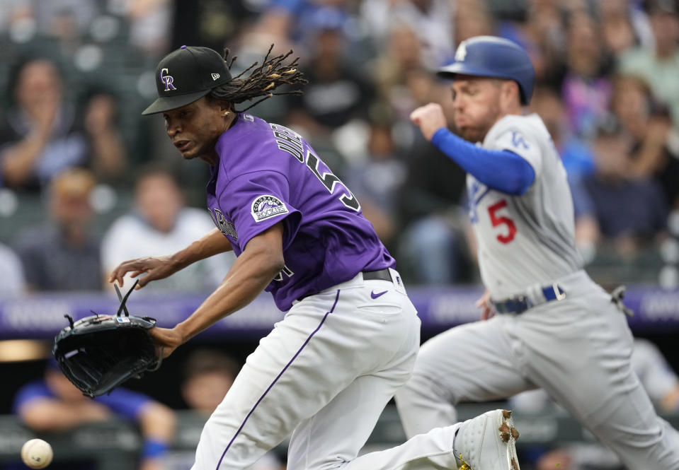 Colorado Rockies starting pitcher Jose Urena, front, races to home plate, reaching for the throw from catcher Elias Diaz after a wild pitch on which Los Angeles Dodgers' Freddie Freeman, right, scored during the first inning of a baseball game Thursday, July 28, 2022, in Denver. (AP Photo/David Zalubowski)