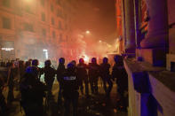 Carabinieri police wearing helmets, foreground, clash with protesters throwing flares, late Friday, Oct. 23, 2020, in Naples, southern Italy. Protesters in Naples, angry over a just-imposed 11 p.m. to 5 a.m. regional curfew and by the local governor’s vow to put the region under lockdown to try to tame surging COVID-19 infections, clashed with police on Friday night. (Alessandro Pone/LaPresse via AP)