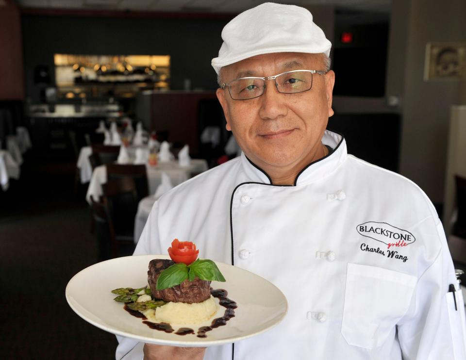 Chef Charles Wang of Blackstone Grille holds a plate of Filet Mignon Au Pouvre in the dining room of his restaurant.