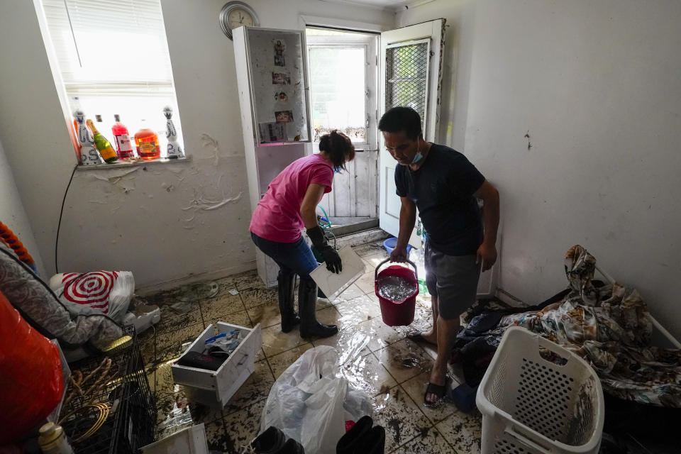 Residents of Peck Ave in the Flushing neighborhood of the Queens borough of New York use buckets to remove water from their basement apartment, Thursday, Sept. 2, 2021, in New York. The remnants of Hurricane Ida dumped historic rain over New York City, with several deaths linked to flooding in the region as basement apartments suddenly filled with water and freeways and boulevards turned into rivers, submerging cars.(AP Photo/Mary Altaffer)