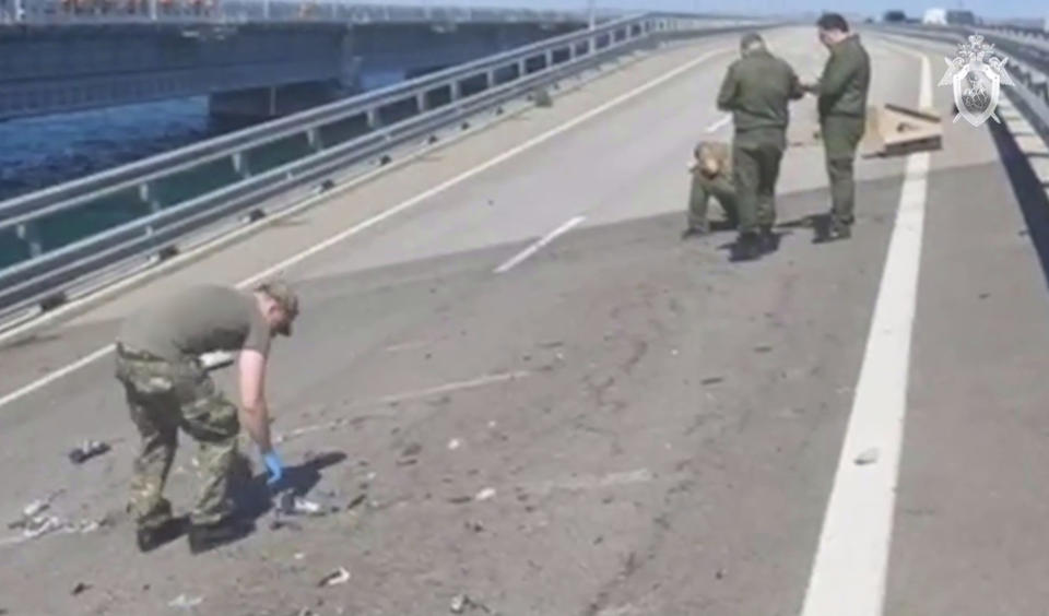In this handout photo taken from video released by the Investigative Committee of Russia on Monday, July 17, 2023, investigators work at an automobile link of the Crimean Bridge connecting Russian mainland and Crimean peninsula over the Kerch Strait not far from Kerch, Crimea. Traffic on the key bridge connecting Crimea to Russia's mainland was halted on Monday, July 17, after reports of explosions that Crimean officials said were from a Ukrainian attack. (Investigative Committee of Russia via AP)