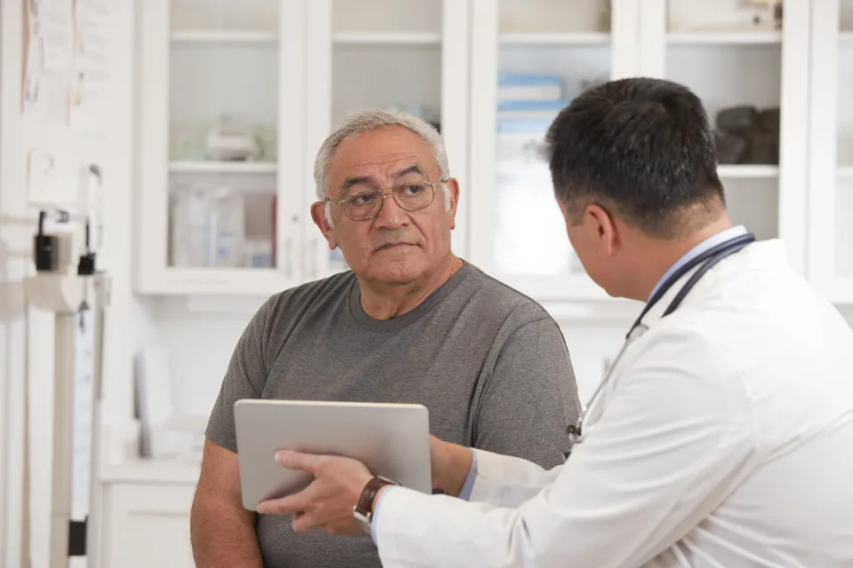 An older man speaking to a health-care professional during a physical or checkup. (Photo via Getty Images)