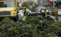 A work crew removes branches from a tree on Mission Street in San Francisco, Thursday, Jan. 17, 2019. Heavy rain, snow and wind pummeled much of California Thursday, causing at least five deaths, leaving thousands without power and forcing wildfire victims threatened by floods to flee their homes. (AP Photo/Jeff Chiu)