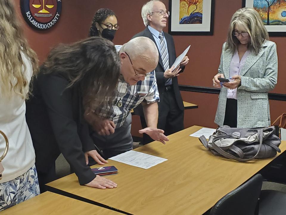 Jeff Titus and attorney Mary Chartier look at the paperwork that closed the double murder case against Titus. Titus was wrongfully convicted in 2002. A federal judge vacated the convictions in Feb. 2023. Kalamazoo County Prosecutor Jeff Getting said at a news conference on Thursday, June 1, 2023, that he decided to not proceed with a new trial. (Marie Weidmayer/Kalamazoo Gazette via AP)