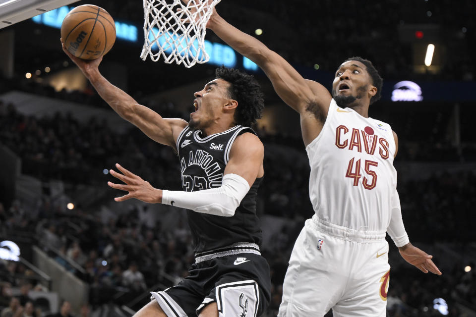 San Antonio Spurs' Tre Jones, left, goes to the basket against Cleveland Cavaliers' Donovan Mitchell during the second half of an NBA basketball game, Monday, Dec. 12, 2022, in San Antonio. San Antonio won 112-111. (AP Photo/Darren Abate)