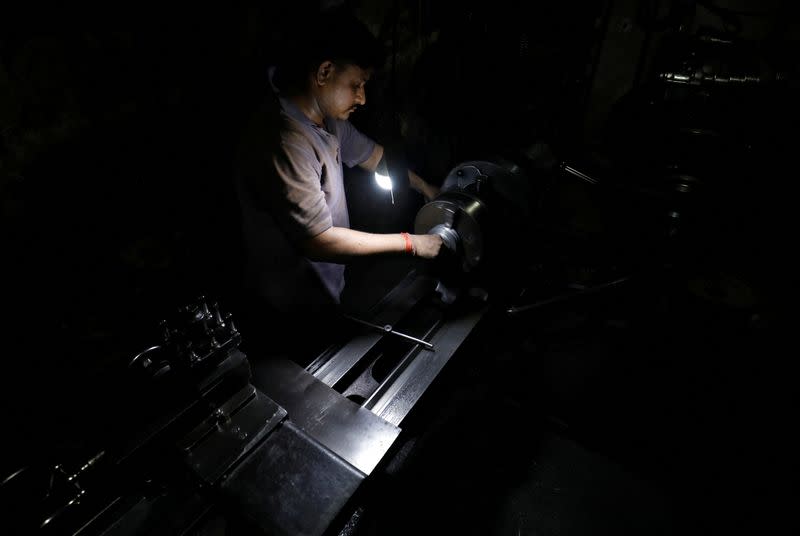 Munna Panchal operates a lathe machine as he fixes a gear box at a small scale manufacturing unit in Ahmedabad