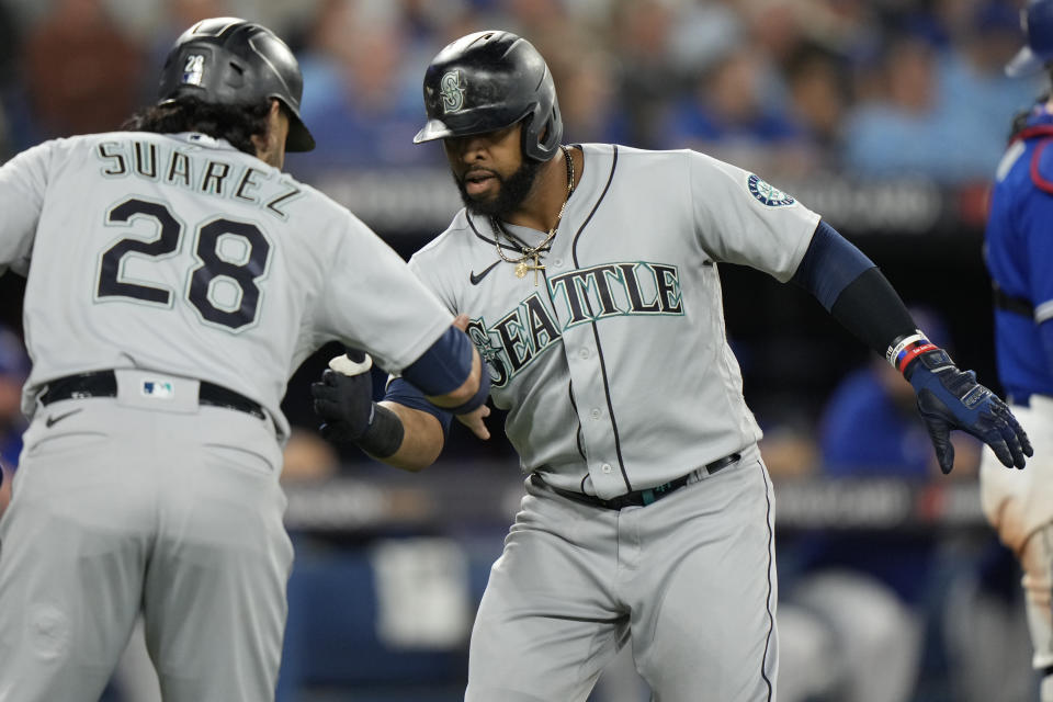 Seattle Mariners designated hitter Carlos Santana, right, celebrates after his three-run home run with teammate Eugenio Suarez (28) during the sixth )inning of Game 2 of a baseball AL wild-card playoff series against the Toronto Blue Jays, Saturday, Oct. 8, 2022, in Toronto. (Frank Gunn/The Canadian Press via AP)