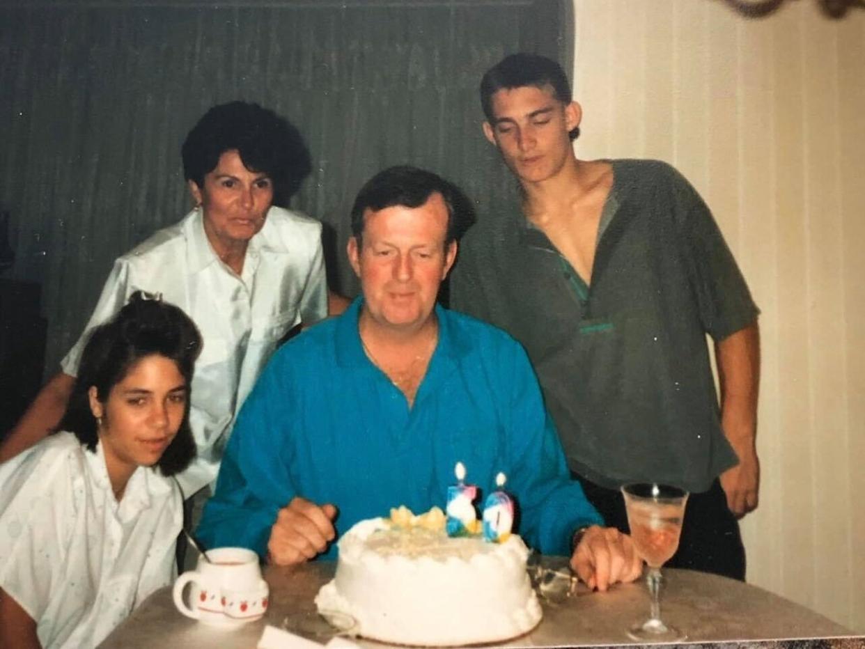 Nicole Johnson with her family sitting at a table with a birthday cake.