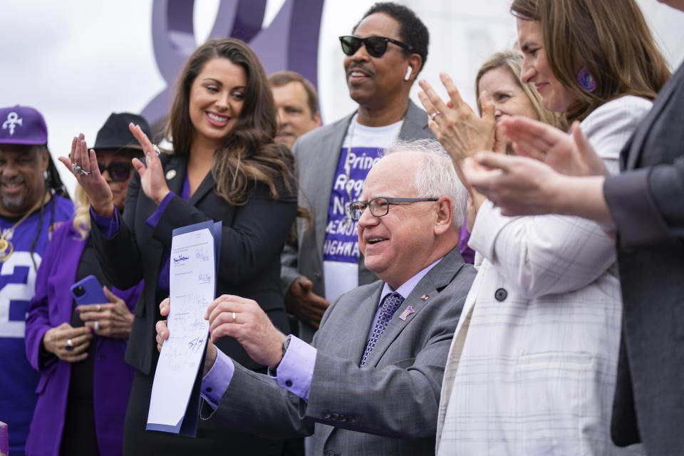 Minnesota Gov. Tim Walz holds up a bill renaming a 7-mile stretch of Highway 5 as "Prince Rogers Nelson Memorial Highway", Tuesday, May 9, 2023, at Paisley Park in Chanhassen, Minn. (Alex Kormann/Star Tribune via AP)