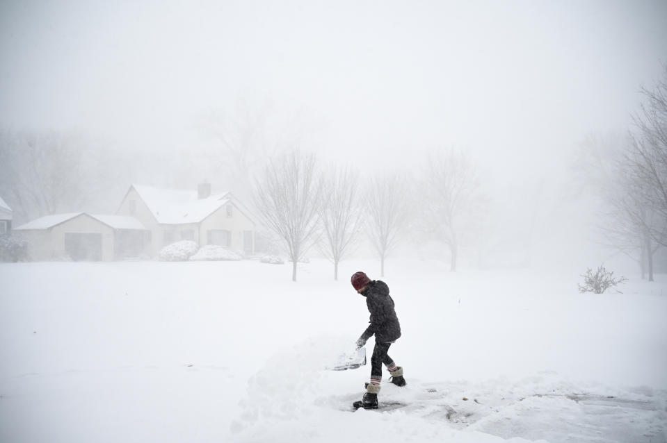 Camilla Cruz, a float nurse at North Memorial Health Hospital, shovels her driveway Wednesday, Dec. 23, 2020 in Robbinsdale, Minn. (Aaron Lavinsky/Star Tribune via AP)