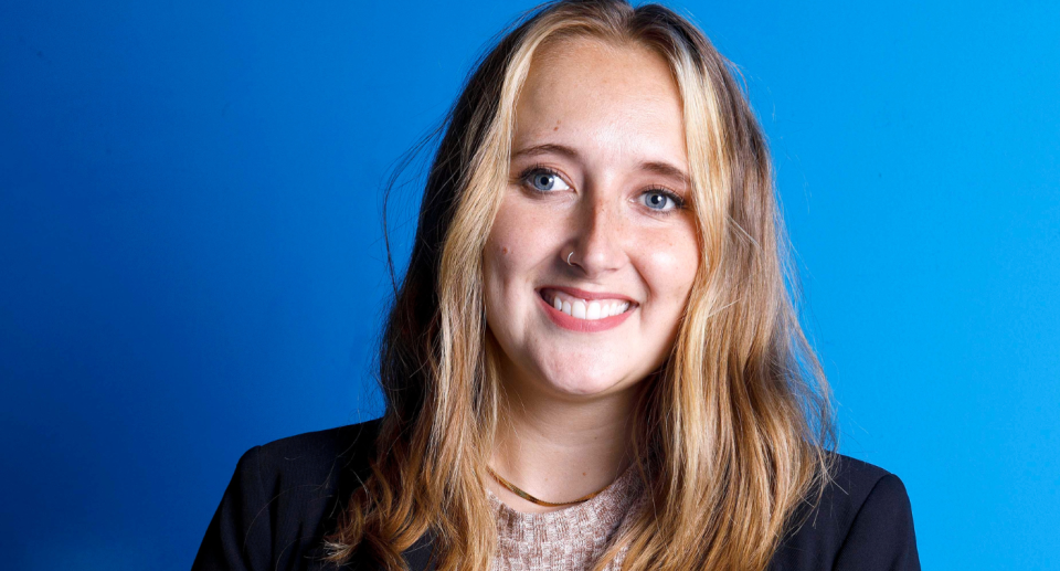 Portrait of a smiling woman on a blue background.