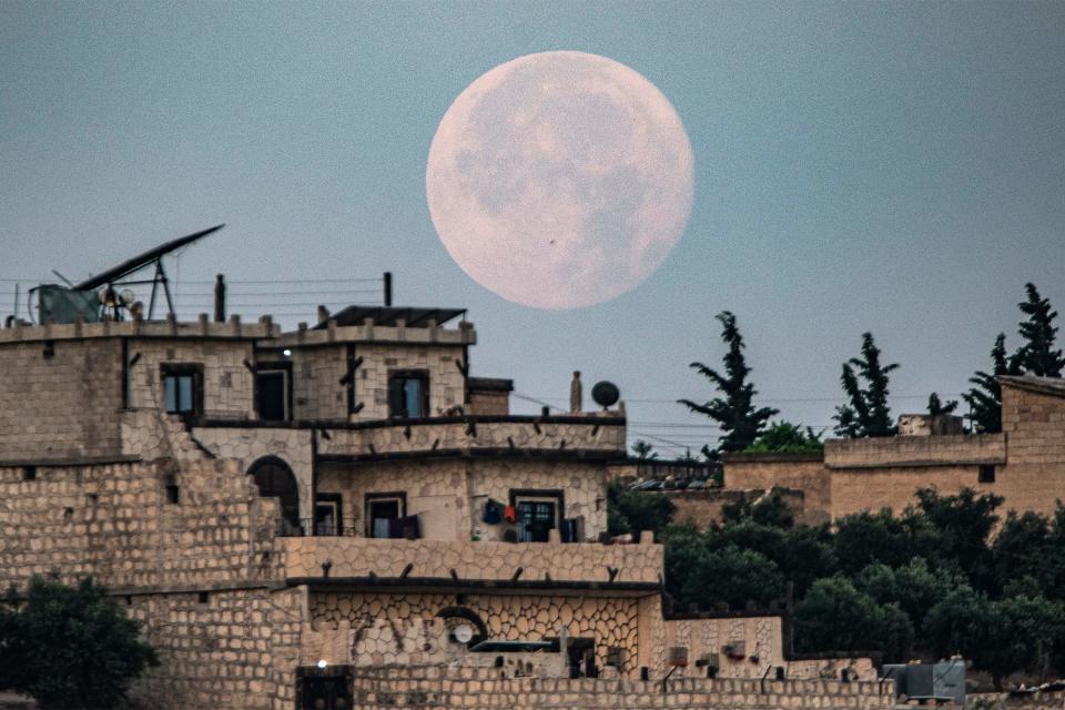 The "buck moon" sets behind buildings in the village of Deir Ballut in the rebel-held Afrin region of Syria's northern Aleppo province early on July 4. The bishops of Aleppo, Syria – Metropolitan Yazigi and Metropolitan Yohanna Ibrahim of the Syriac Orthodox Church – disappeared 10 years ago while seeking the release of two kidnapped priests.