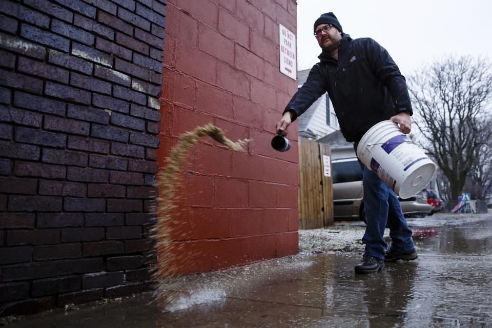 Kevin Wahlert of Pleasant Hill spreads salt on the sidewalks outside his bar, The Fremont, on Monday, Jan. 16, 2017, in Des Moines, Iowa. Travel remains hazardous in parts of Iowa and Nebraska as ice storms move north and east through the states. (Brian Powers/The Des Moines Register via AP )