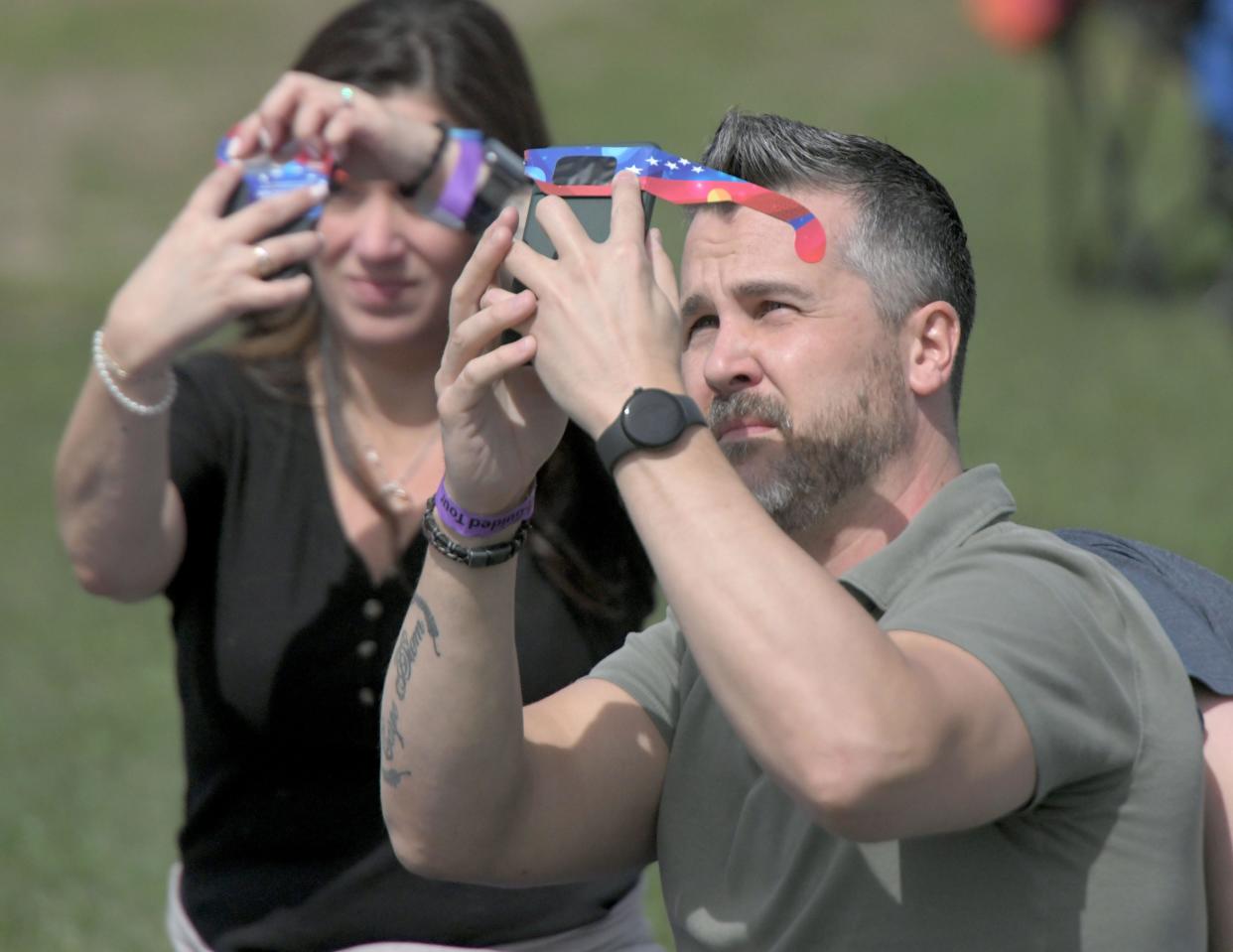 Shutterbugs use eclipse glasses as a filter for their phones during the eclipse.