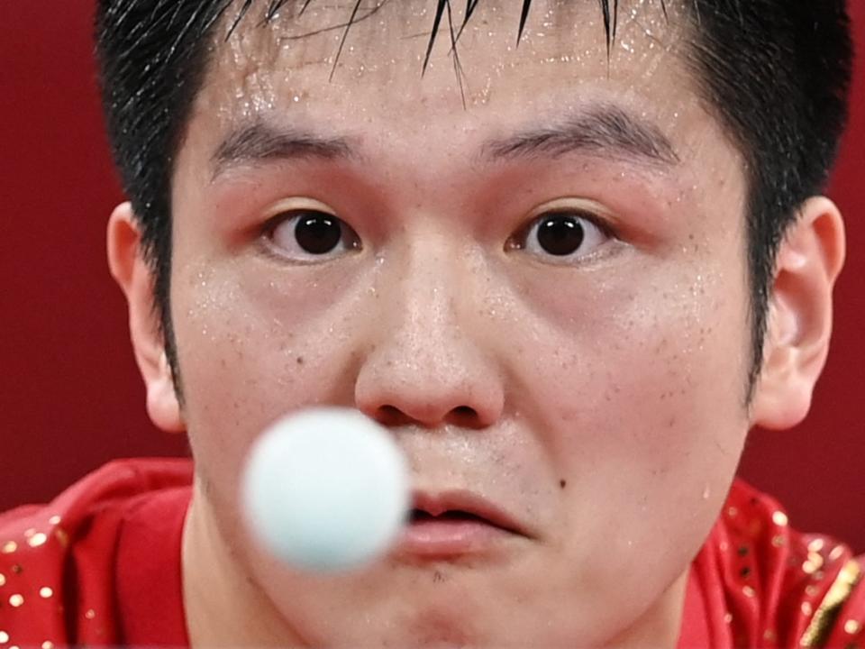 China's Fan Zhendong stares at a ping pong ball in the air at the Tokyo Olympics.