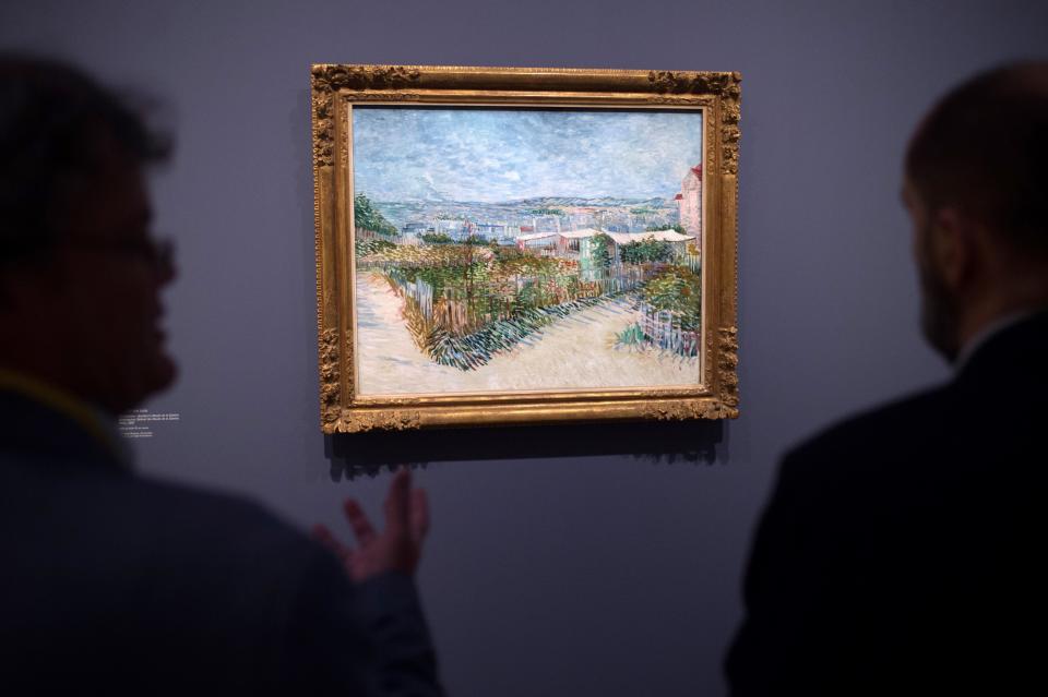 Men look at a painting by Vincent Van Gogh entitled 'Montmartre: Behind the Moulin de la Galette' during the exhibition 'Van Gogh in Provence: Modernizing Tradition' at the Fondation Vincent Van Gogh Arles on May 13, 2016 in Arles, southern France.&nbsp;