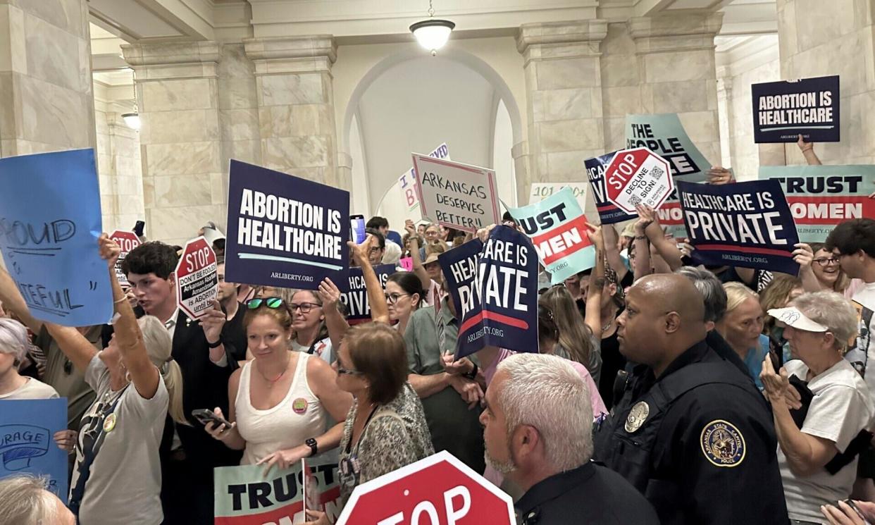 <span>Supporters and opponents of a proposed ballot measure to scale back Arkansas' abortion ban hold signs outside the old supreme court chamber at the state capitol in Little Rock, Arkansas, on 5 July 2024. </span><span>Photograph: Andrew DeMillo/AP</span>