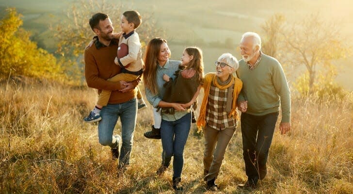 happy-multi-generation-family-talking-while-taking a walk-on-a-hill-SmartAsset-Sandwich-Generation-2