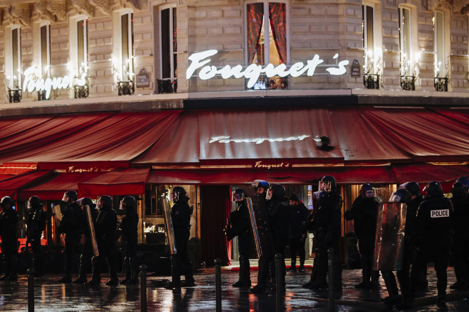 Riot police officers take position on the Champs Elysees Avenue as the famous restaurant 'Fouquet's' is seen in the background during a yellow vests demonstration in Paris Saturday, Dec. 22, 2018. France's yellow vest protesters, who have brought chaos to Paris over the past few weeks with their economic demands, demonstrated in sharply reduced numbers Saturday at the start of the Christmas and New Year holidays. (AP Photo/Kamil Zihnioglu)