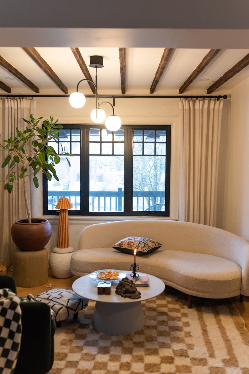 White living room with black accent and large circled fabric couch opposite to a black chair.