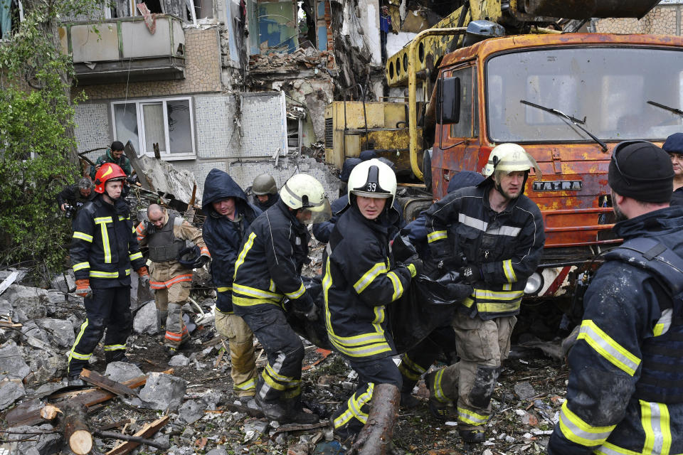 Rescuers carry the body of a civilian at a site of an apartment building destroyed by Russian shelling in Bakhmut, Donetsk region, Ukraine, Wednesday, May 18, 2022. (AP Photo/Andriy Andriyenko)