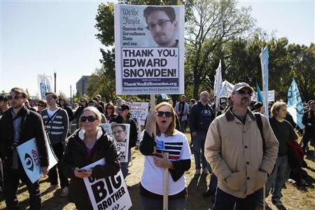 Demonstrators hold signs supporting fugitive former NSA contractor Edward Snowden as they gather for the "Stop Watching Us: A Rally Against Mass Surveillance" near the U.S. Capitol in Washington, October 26, 2013. REUTERS/Jonathan Ernst