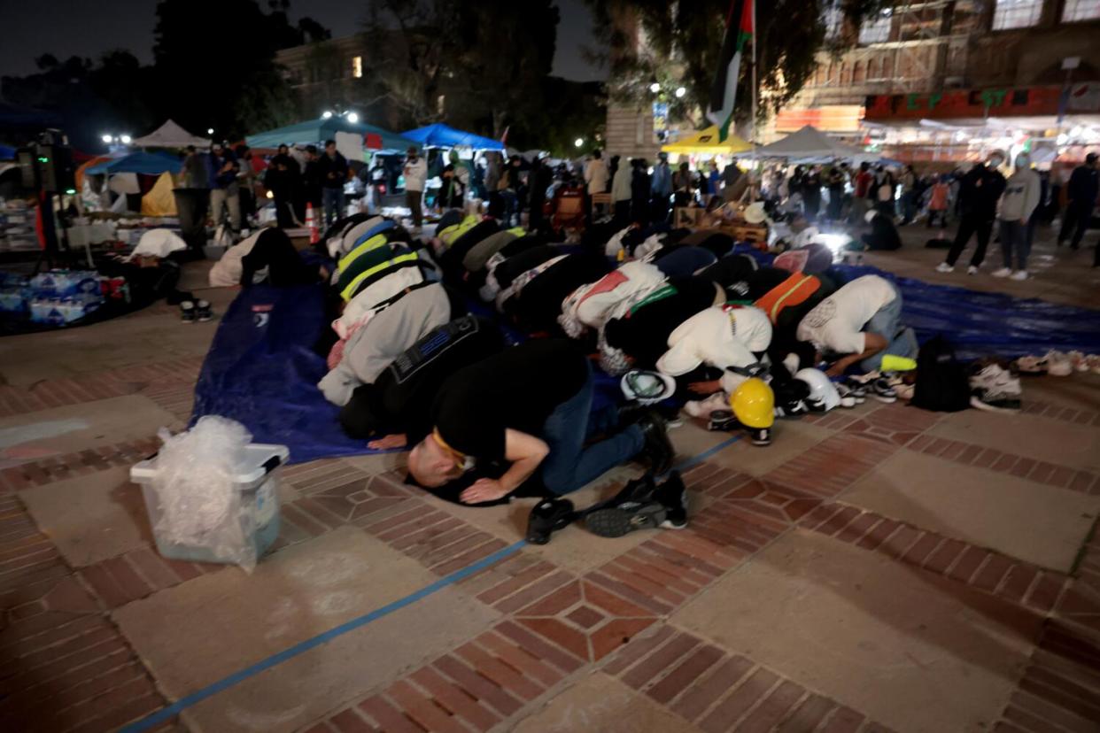 Pro-Palestinian protesters kneel, press their heads to the ground and pray in front of Royce Hall on the campus of UCLA.