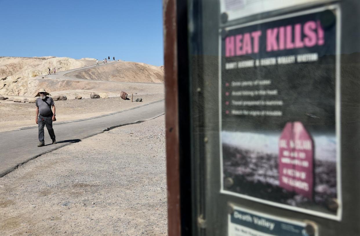 PHOTO: A 'Heat Kills' sign is posted as visitors walk nearby, April 23, 2024, in Death Valley National Park, Calif. (Mario Tama/Getty Images)