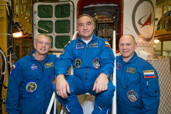 In the Integration Facility at the Baikonur Cosmodrome in Kazakhstan, NASA astronaut Steve Swanson (left) and Alexander Skvortsov (center) and Oleg Artemyev of Roscosmos pose for pictures in front of their Soyuz TMA-12M spacecraft March 21, 201