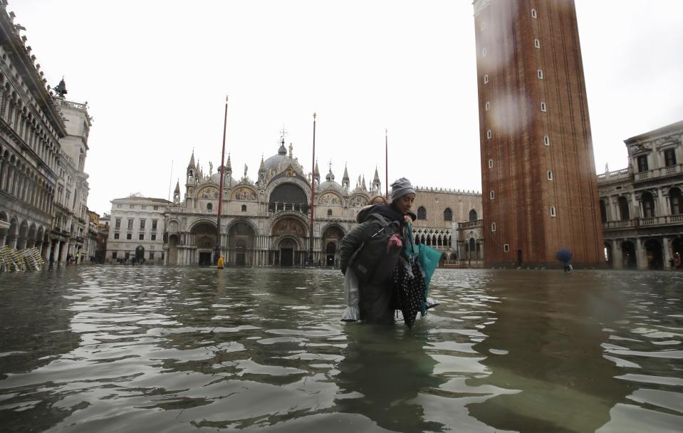 A woman carries her daughter in St Mark's Square (AP)