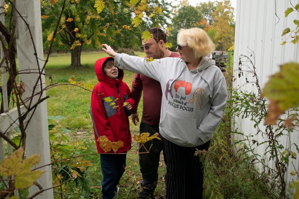 Annette Kramer, 54, right, reaches out to her grandson Kire Dumont, 10, along side her partner William Petrusha, 35, as they walk in their Corunna backyard on Monday, Oct. 16, 2023. Kramer, who is on strike at GM, took out a $4,000 strike loan from a credit union.