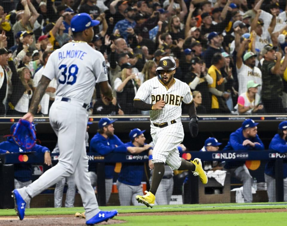 San Diego's Trent Grisham scores as Dodgers relief pitcher Yency Almonte walks back to the mound.