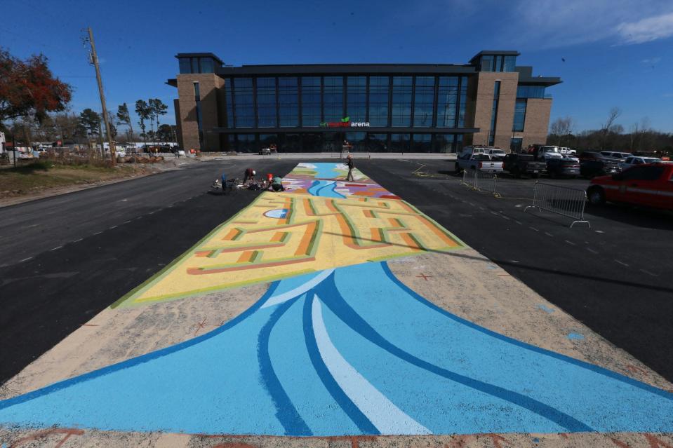 Artists Nae&#39;Keisha Jones, Alfredo Martinez, and Brian MacGregor work on a mural on the ground just outside the new Enmarket Arena. Xavier Hutchins is the fourth artist with the team that designed the mural.