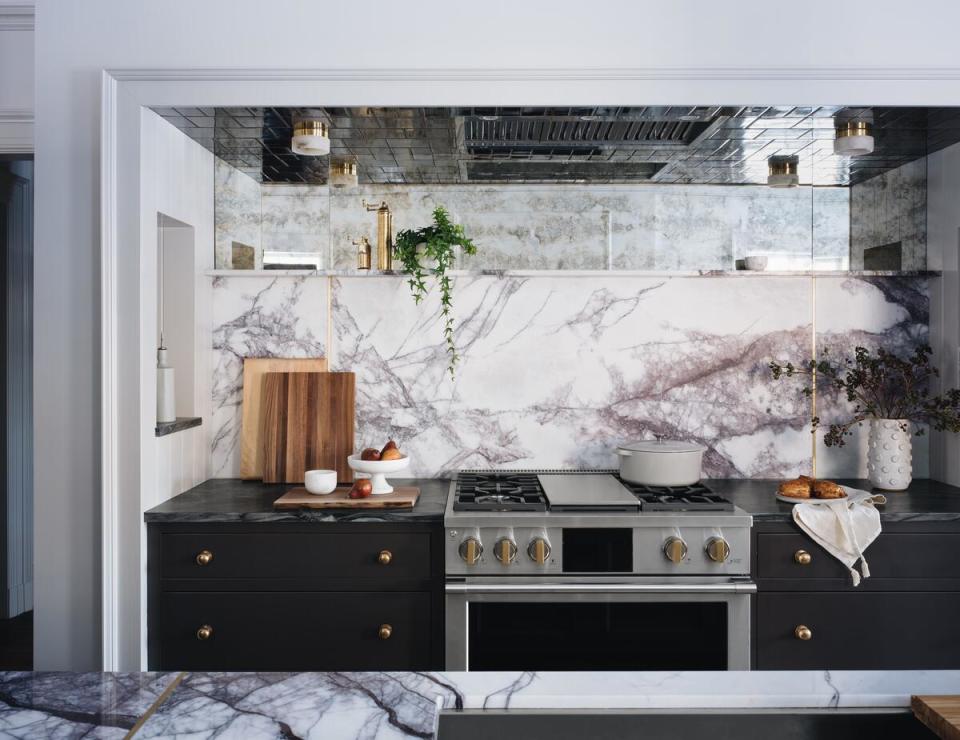 For the kitchen backsplash of a colonial home in Cedar Rapids, Michigan, designer Jean Stoffer used brass accents to conceal the seams between the central marble mini-slab and two side pieces