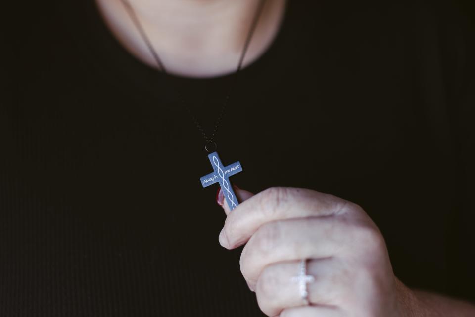 Debbie Navejas Aguilar holds the cremation pendant that she bought to have both her father and mother’s ashes close to her heart.