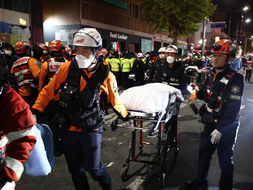 Emergency services transport a person after a stampede during a Halloween celebration in Seoul, South Korea.
