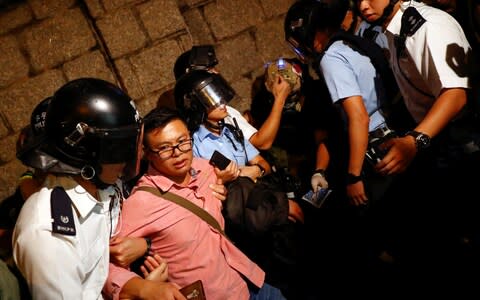 Police officers assist a man saying he is a Chinese tourist outside the government headquarters during a general strike in Hong Kong - Credit: &nbsp;REUTERS